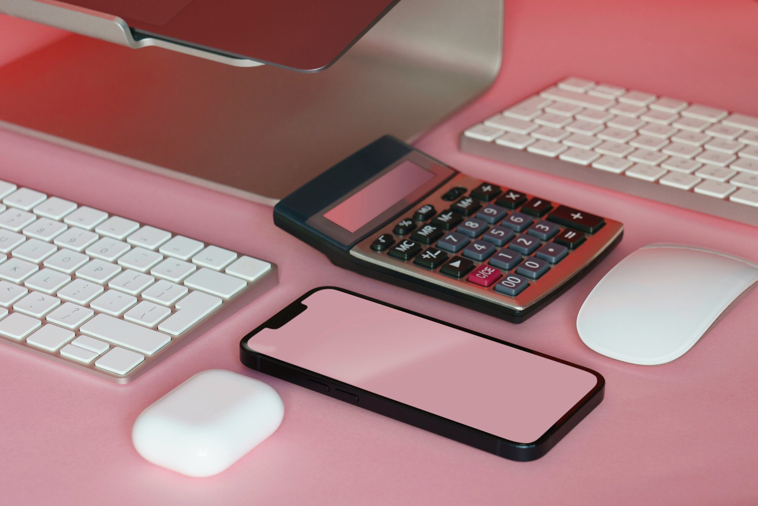 Pink desktop with calculator, phone and other computing devices - Jakub Zerdzicki 2024